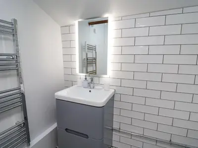 a white bathroom with a sink and a mirror at Ty Bach Twt in Llandysul