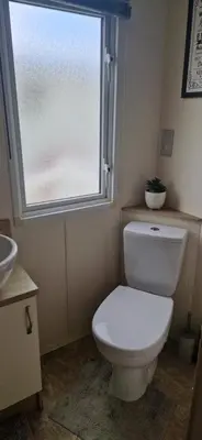 a bathroom with a white toilet and a window at Sea View Caravan - Aber Bay Holiday Park in Aberystwyth