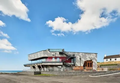 a building in front of a blue sky with clouds at Sea View Caravan - Aber Bay Holiday Park in Aberystwyth
