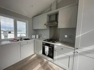a kitchen with white cabinets and a stove top oven at WH - Smugglers Lodge in Aberaeron