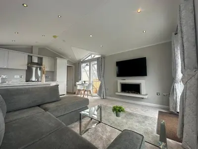 a living room with a couch and a tv at WH - Smugglers Lodge in Aberaeron