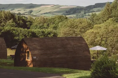 a small wooden building with an umbrella in the grass at Brecon by Wigwam Holidays in Brecon