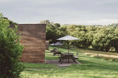 a picnic table with an umbrella in the grass at Brecon by Wigwam Holidays in Brecon