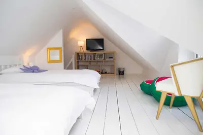 a attic bedroom with two beds and a chair at Trem y Don New Quay in New Quay