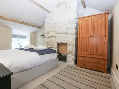 a bedroom with a bed and a stone fireplace at Islwyn in Bala