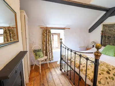 a bedroom with a bed and a chair in a room at Ty Newydd Uchaf in Dolgellau
