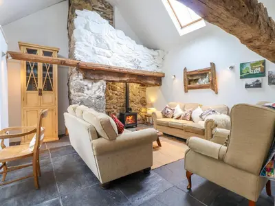 a living room with two couches and a stone fireplace at Ty Newydd Uchaf in Dolgellau