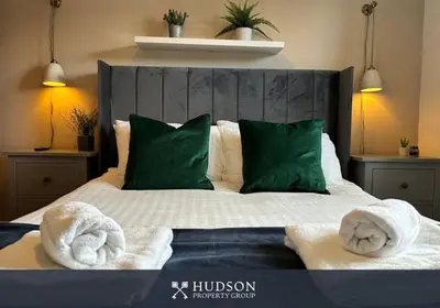a bedroom with a bed with green pillows and towels at 3 Bedroom Modern Property with Parking in Shrewsbury
