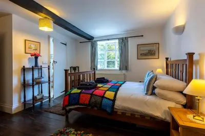 a bedroom with a bed with a colorful blanket at RYTON GRANGE FARMHOUSE to sleep 12 in Shrewsbury