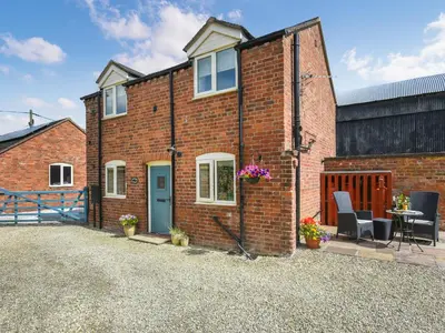 a brick house with a blue door and a patio at Lavender Cottage in Shrewsbury
