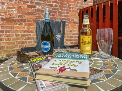 a table with a book and a bottle of wine at Lavender Cottage in Shrewsbury