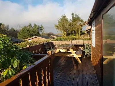 a wooden deck with a wooden picnic table on it at Gwel-y-Cwm - Valley View in Trawsfynydd