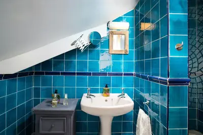 a bathroom with a sink and a blue tiled wall at Morwylfa Borth and Ynyslas in Borth