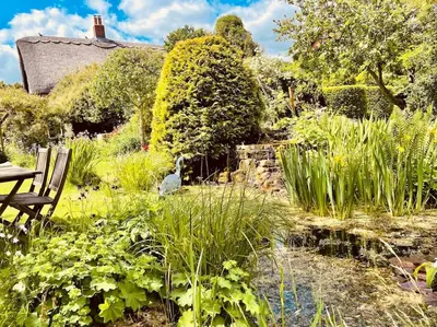 a garden with a table and chairs and plants at Tawny Owl Barn in Leintwardine