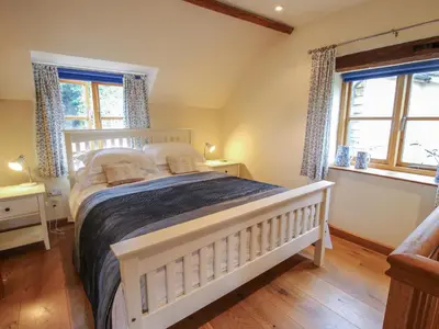 a bedroom with a white bed and two windows at New Inn Cottage in Church Stretton