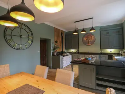 a kitchen with a table and a clock on the wall at Llwynderw Hall in Llanwrtyd Wells