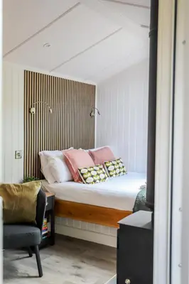 a bedroom with a bed with pillows and a chair at Nant Gwenyn - Hafan Hideaways Eryri in Llanymawddwy