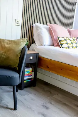 a bedroom with a bed with a chair and a side table at Nant Gwenyn - Hafan Hideaways Eryri in Llanymawddwy