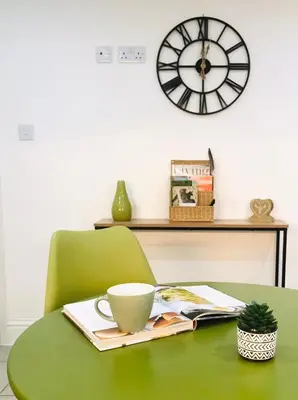 a green table with a coffee cup and a clock at Bell Cottage by Ludlow Castle with onsite parking in Ludlow