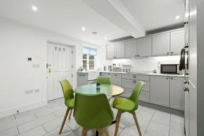 a kitchen with a table and green chairs at Bell Cottage by Ludlow Castle with onsite parking in Ludlow