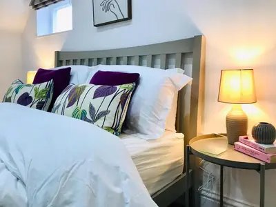 a bedroom with a bed with pillows and a lamp at Bell Cottage by Ludlow Castle with onsite parking in Ludlow