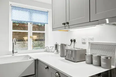 a kitchen with white counters and a sink and a window at Bell Cottage by Ludlow Castle with onsite parking in Ludlow