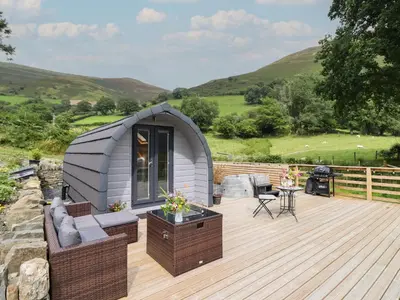 a tiny house on a deck with a table and chairs at Caban Tirion in Machynlleth