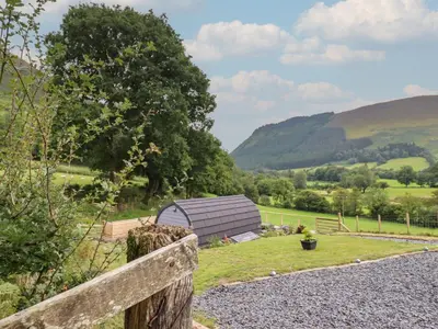 a barn in a field with a fence at Caban Tirion in Machynlleth