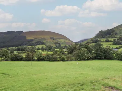 a green field with hills in the background at Caban Tirion in Machynlleth