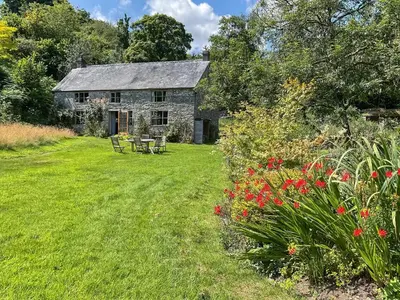 an old stone house with a garden and flowers at Cwmberwyn in Llansaintfraed in Elvel