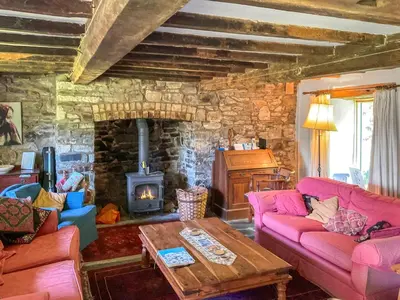 a living room with pink couches and a stone fireplace at Cwmberwyn in Llansaintfraed in Elvel