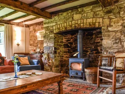 a stone fireplace in a living room with a wood stove at Cwmberwyn in Llansaintfraed in Elvel