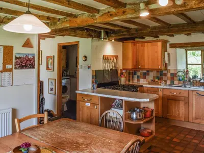 a kitchen with wooden cabinets and a table in it at Cwmberwyn in Llansaintfraed in Elvel