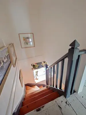 a staircase in a house with paintings on the wall at Cosy Welsh Town Cottage in Brecon