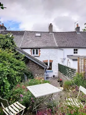 a white house with a table and chairs in a yard at Cosy Welsh Town Cottage in Brecon
