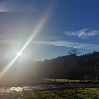 a sun shining over a field with the sun shining at Owl Cabin in Llanbrynmair