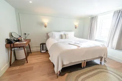 a bedroom with a large white bed and a table at Glan Yr Afon in Pennal