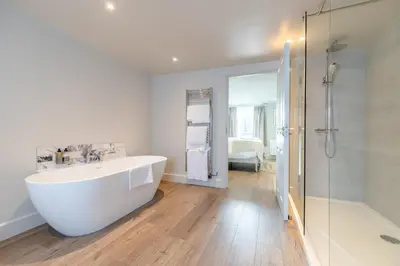 a bathroom with a white tub and a shower at Glan Yr Afon in Pennal