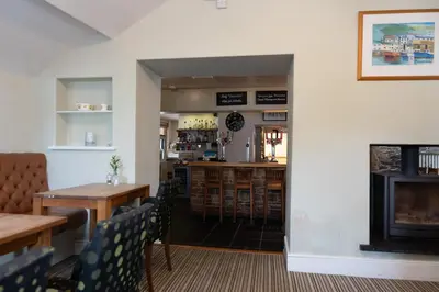 a dining room with a table and a fireplace at Glan Yr Afon in Pennal