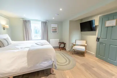 a bedroom with a bed and a tv and a chair at Glan Yr Afon in Pennal
