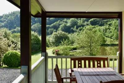 a view from the porch of a house with a table and chairs at Secluded Farmhouse with Private Lake in Llanwrda