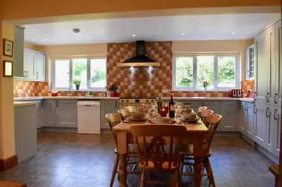 a kitchen with a table and chairs in it at Secluded Farmhouse with Private Lake in Llanwrda