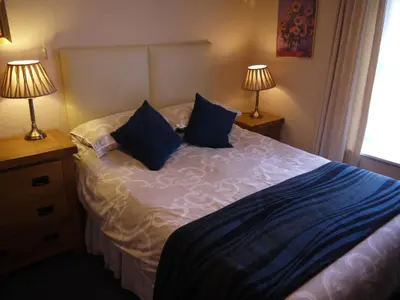 a bedroom with a bed with blue pillows and two lamps at Ivy House B&B in Dolgellau