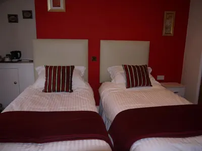 two beds in a room with a red wall at Ivy House B&B in Dolgellau