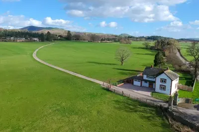 a small house in a green field with a road at Marrington Lodge in Chirbury