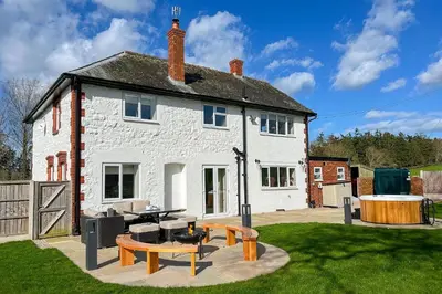 a white house with a picnic table and a grill at Marrington Lodge in Chirbury