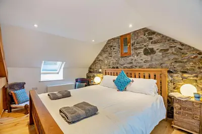 a bedroom with a large bed and a stone wall at 1 Bed in Brithdir oc-w30045 in Rhydymain