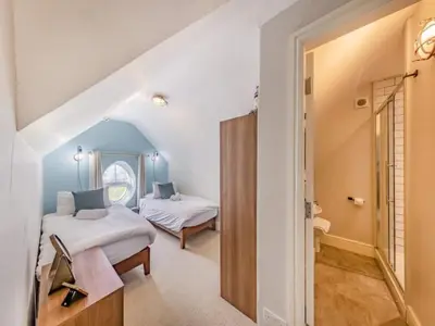 a bedroom with two beds and a door to a bathroom at Pencartref- Luxurious Seaside Apartment Aberdovey in Aberdyfi