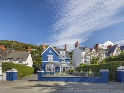 a blue and white house in a residential neighborhood at Pencartref- Luxurious Seaside Apartment Aberdovey in Aberdyfi