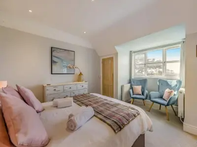 a bedroom with a large bed and two chairs at Pencartref- Luxurious Seaside Apartment Aberdovey in Aberdyfi